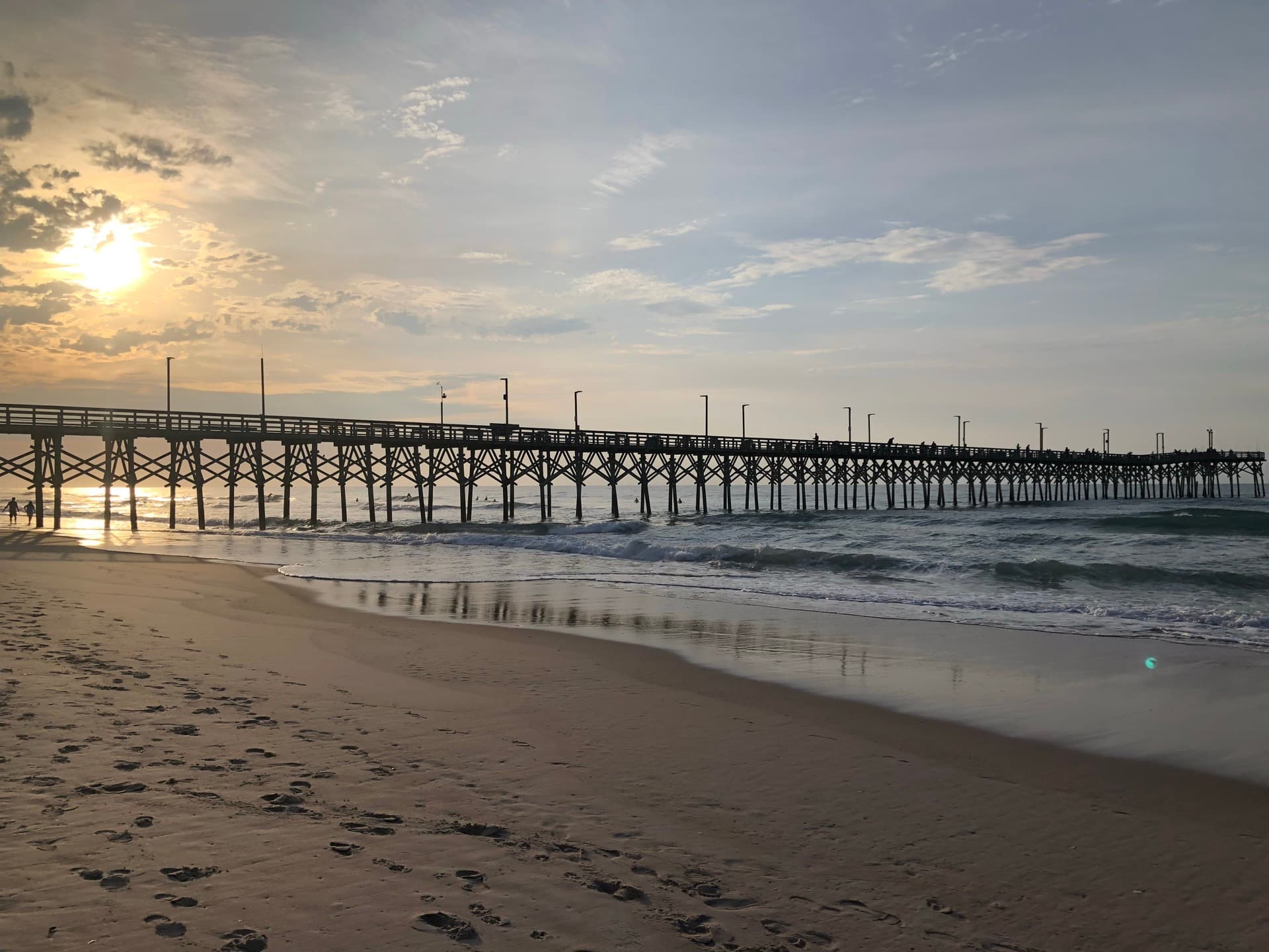 Topsail Beach pier at sunset, sky reflected on wet sand