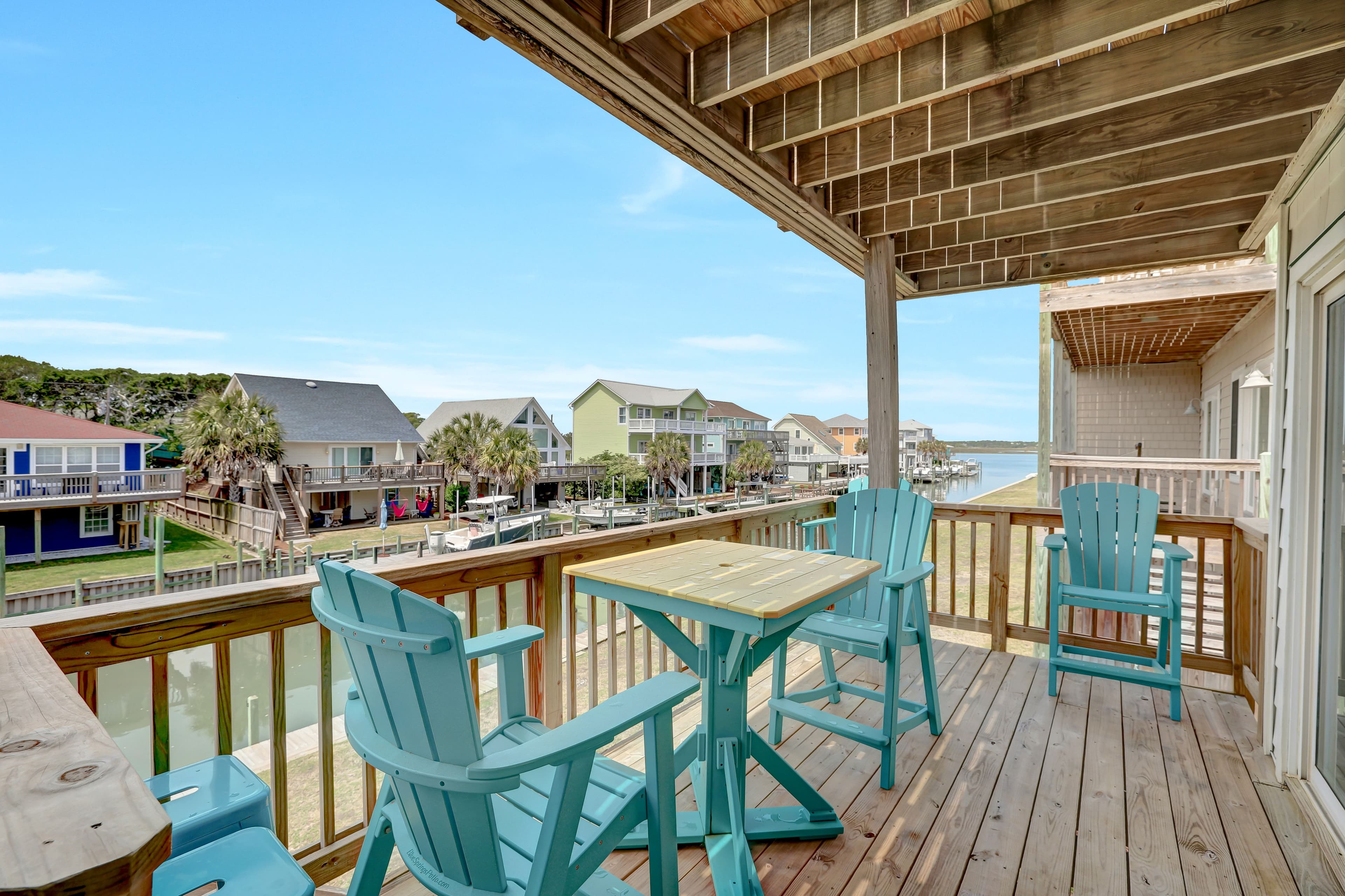 Covered canal-view balcony with coastal seating for coffee, dining, and sunsets