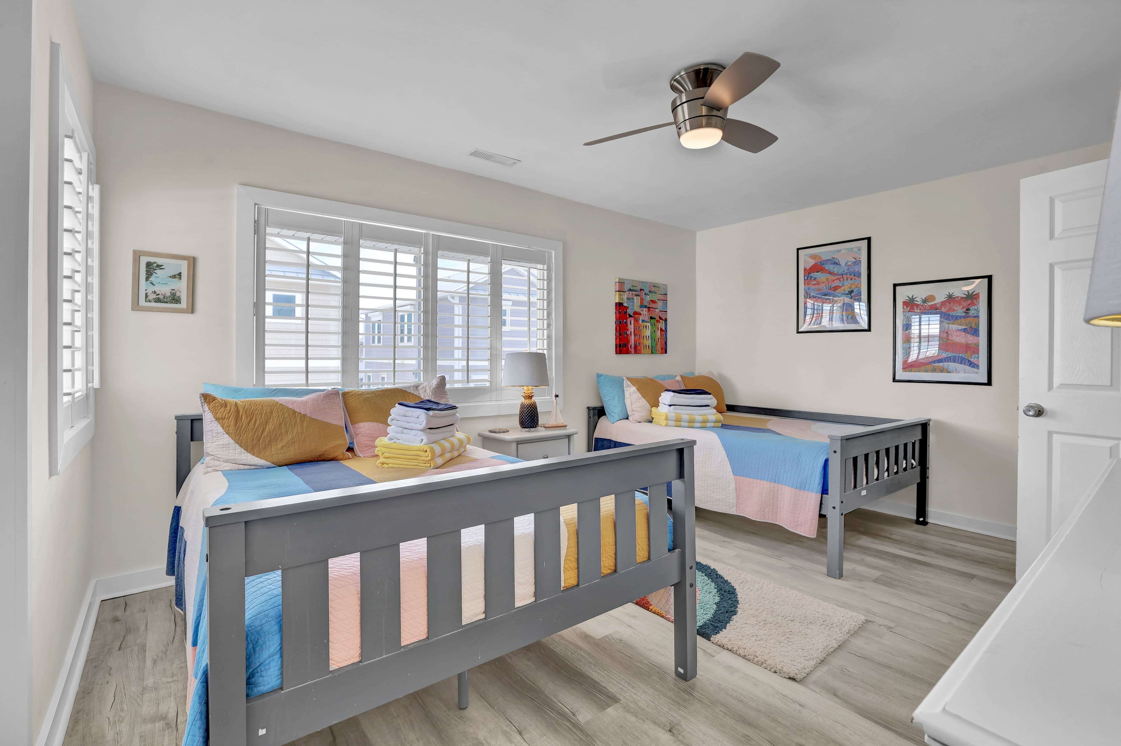 Bright twin bedroom with natural light, ceiling fan, and cheerful decor