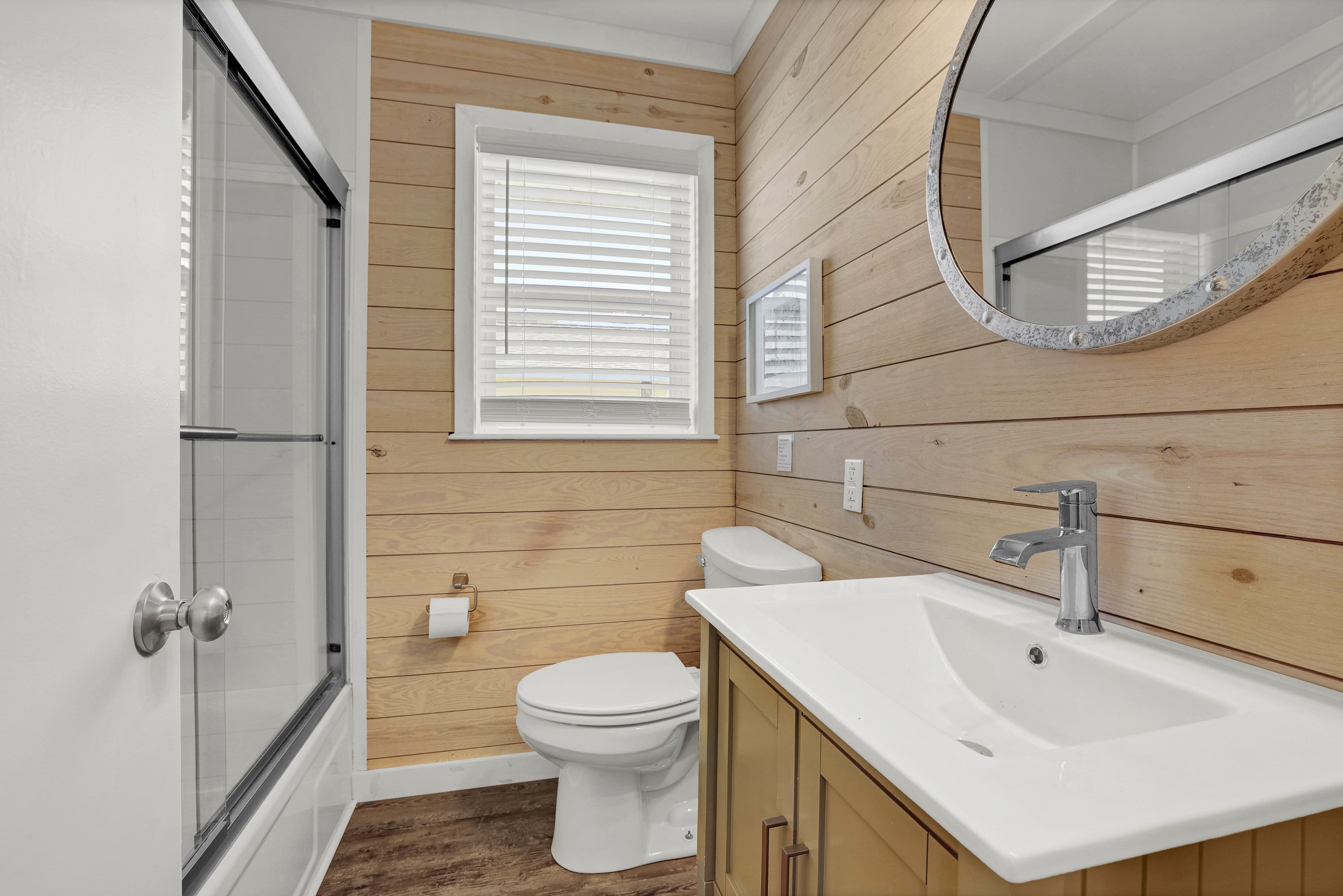 Bright wood-accented bathroom with modern vanity and shower-tub combo