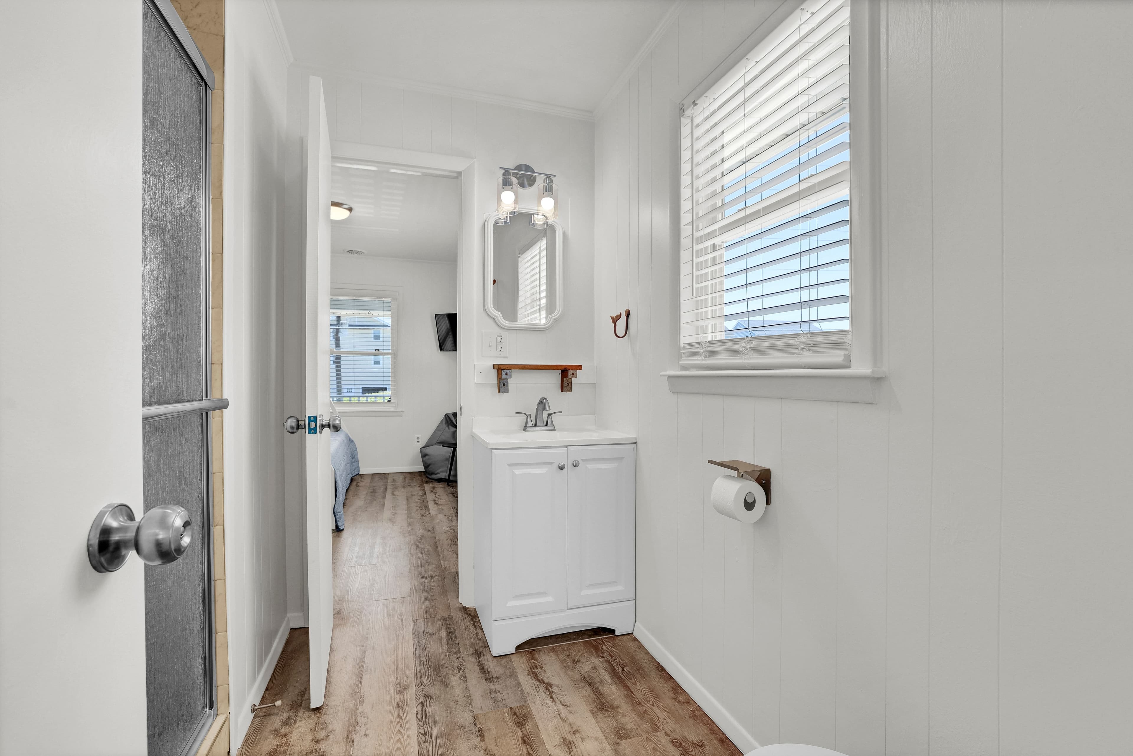 Bright bathroom with natural light, walk-in shower, and bedroom access