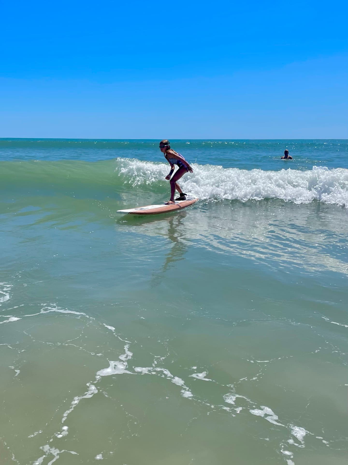 A kid catching a wave on a surfboard at Topsail Island, turquoise water